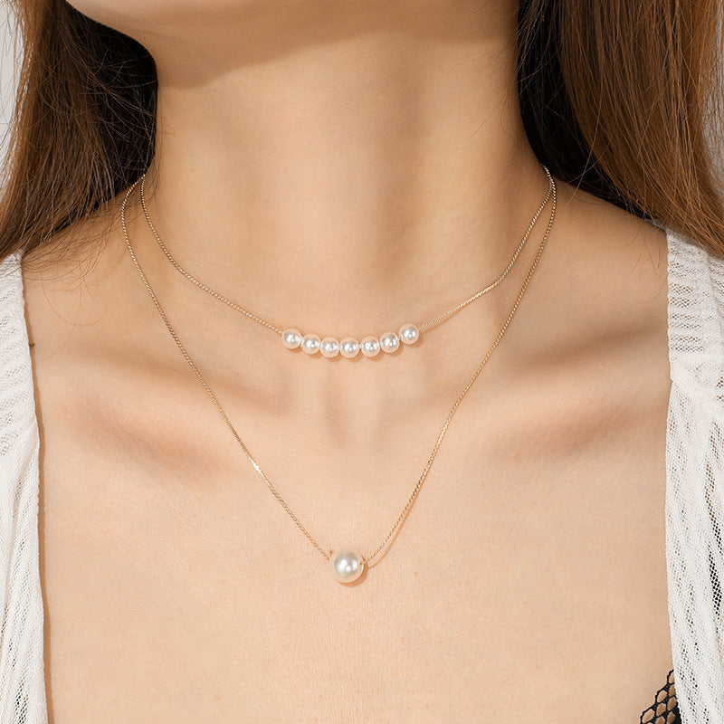 A woman wearing a white shirt showcasing a gold-tone layered pearl necklace.