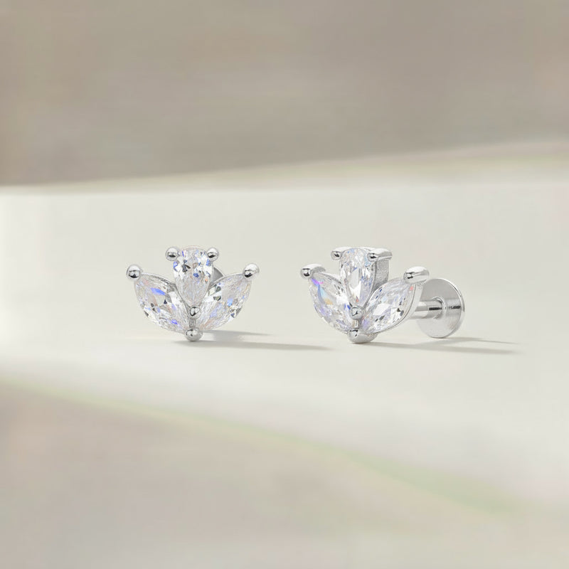 Pair of silver earrings with clear gemstones on a blurred background