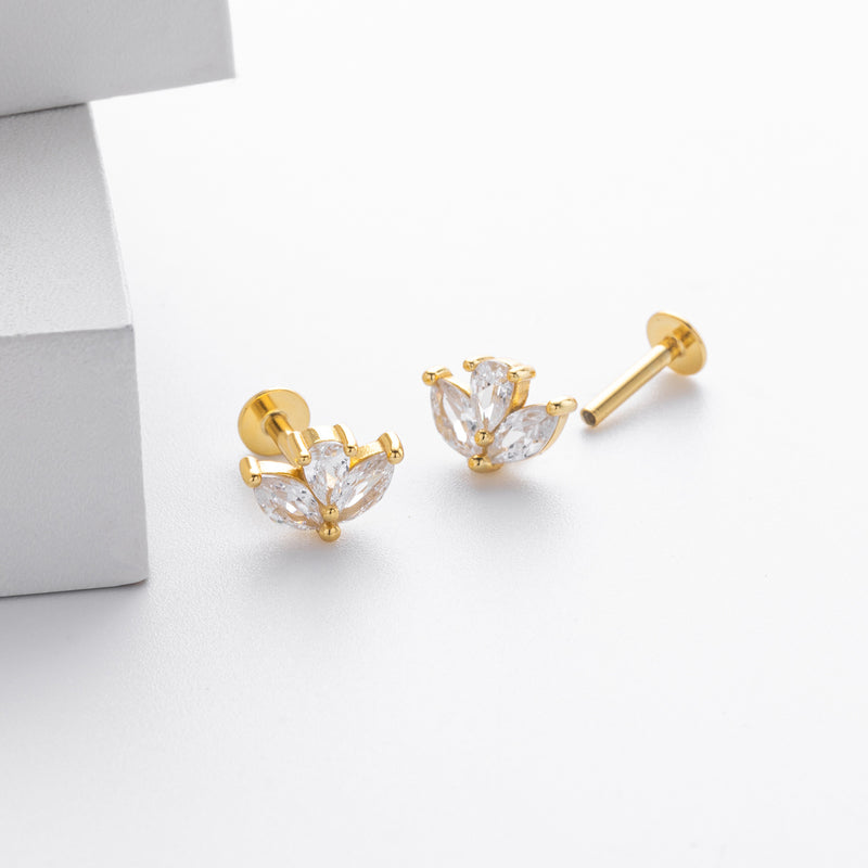 Gold earrings with clear gemstones on a light gray background