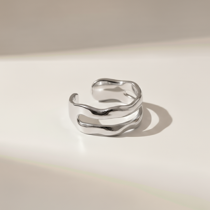 Silver ring with wavy design on a beige background