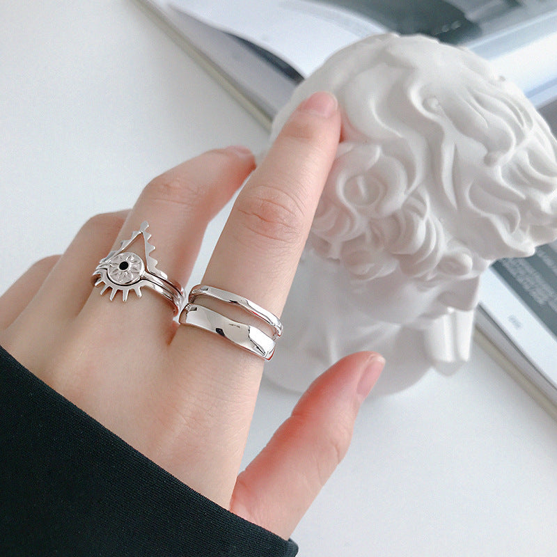 Hand wearing two silver rings with a decorative object in the background