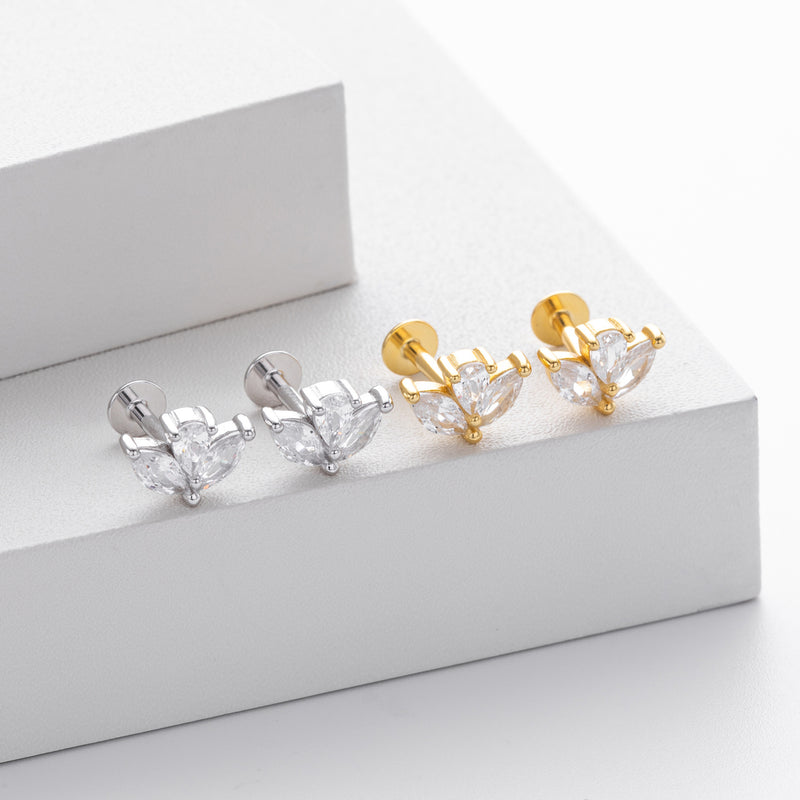 Pair of gold and silver flower-shaped earrings on a white box.